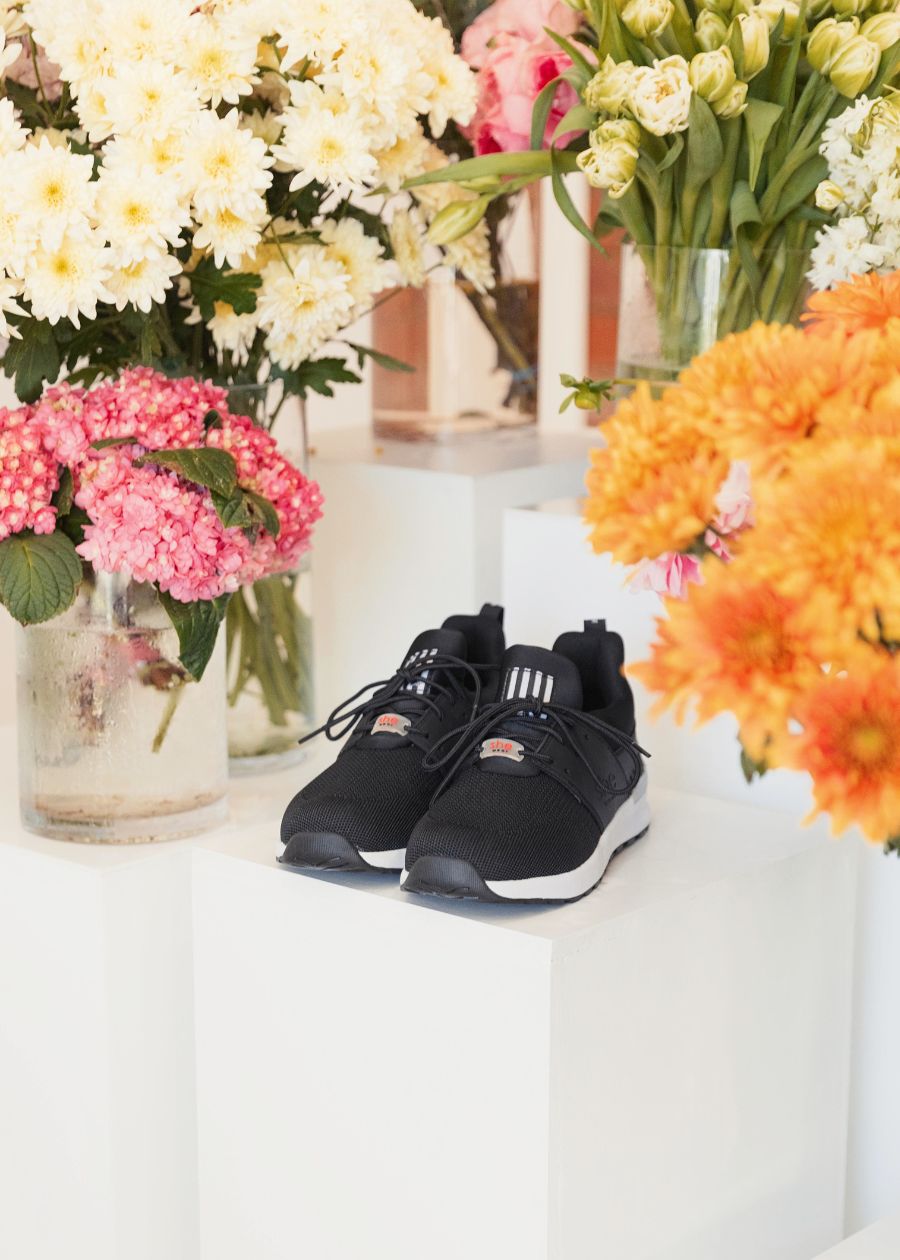 black active sneakers on a stand with flowers