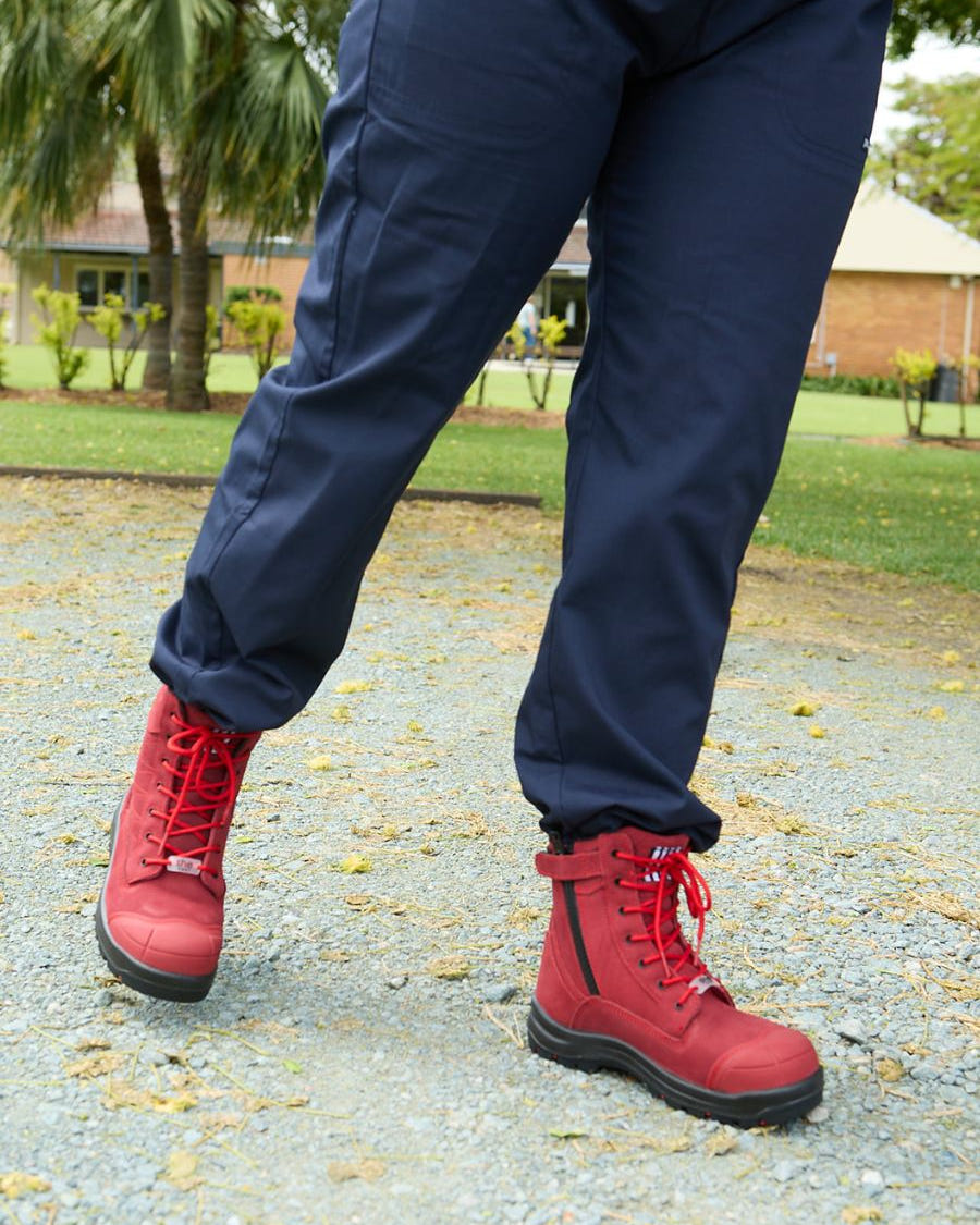 Person walking on gravel in red lace-up safety boots.