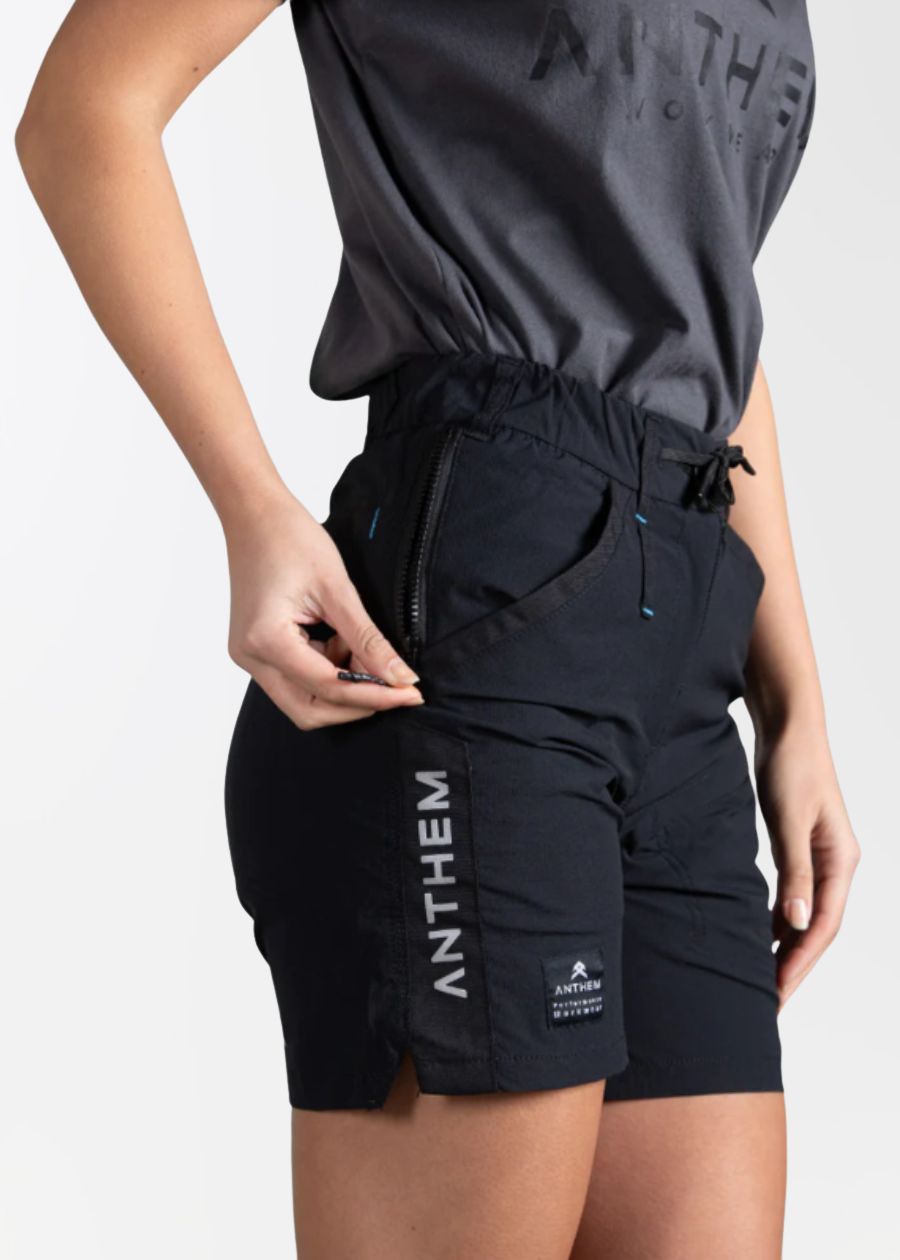 Woman zipping up pocket on black light weight work shorts.