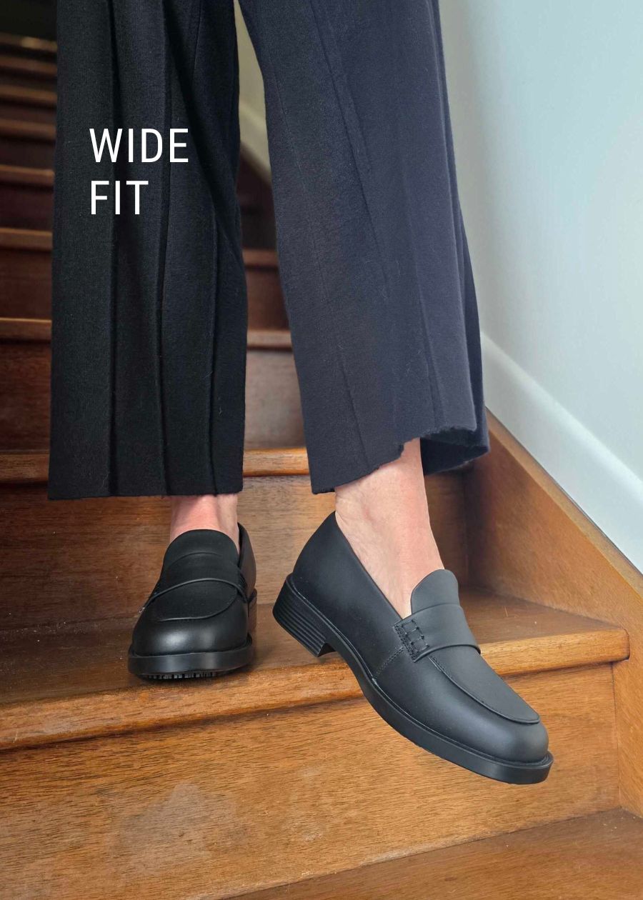 Wide fit black leather loafers on wooden staircase