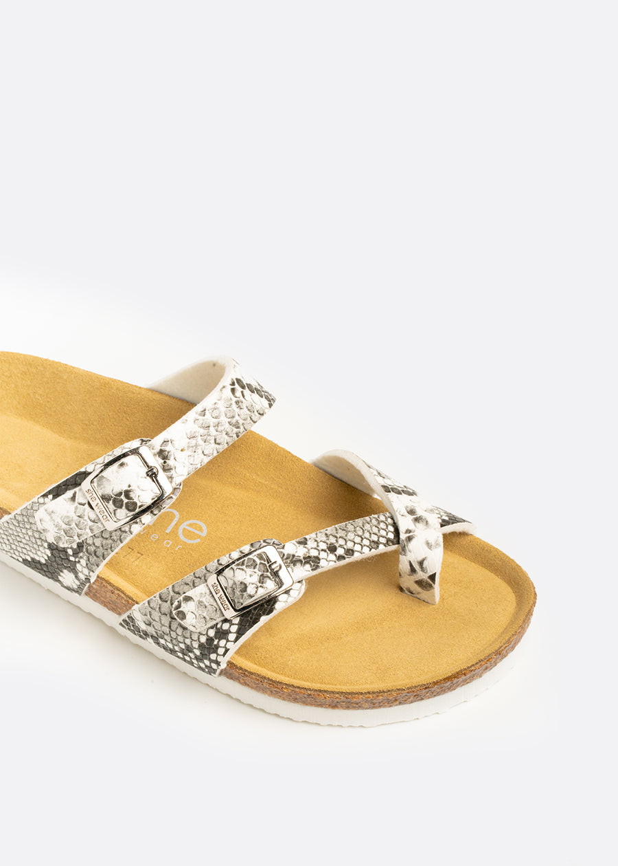 A cork sandal with cross toe strap. Black and white snakeskin print leather straps across the sandal