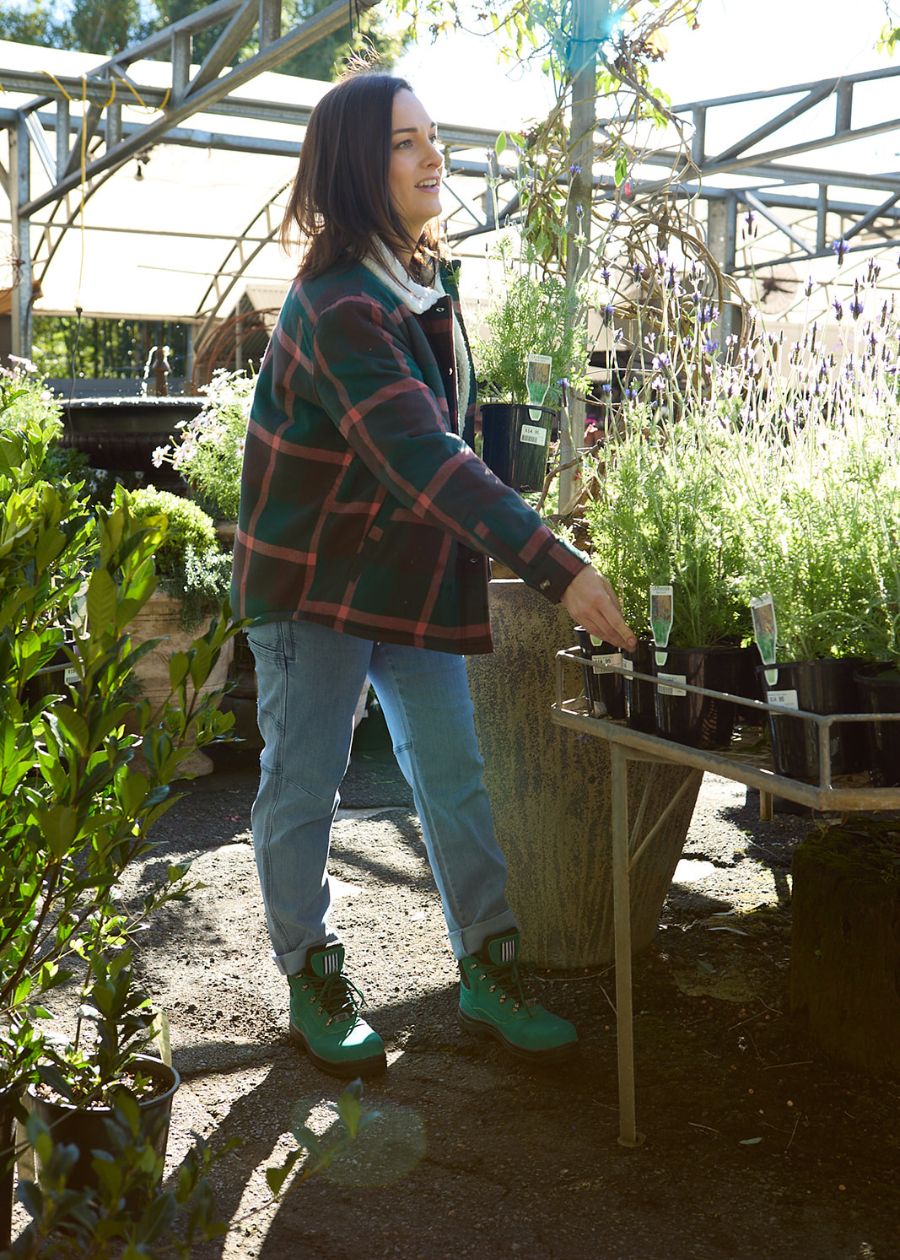 Woman grabbing plants in green sherpa heritage hoodie.
