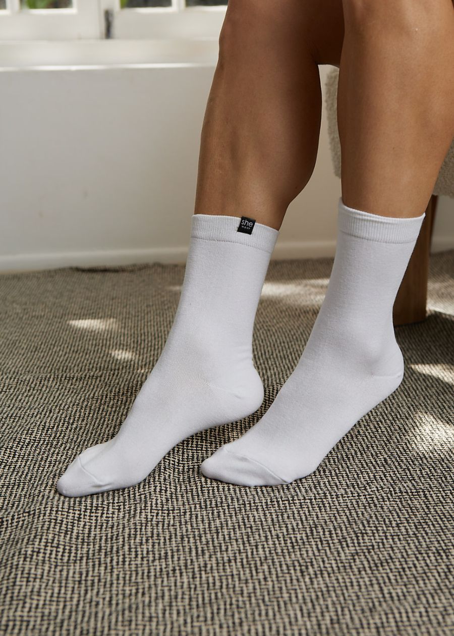 Interior shot of a woman's legs wearing a clean pair of comfortable white bamboo everyday socks. They are crew length.