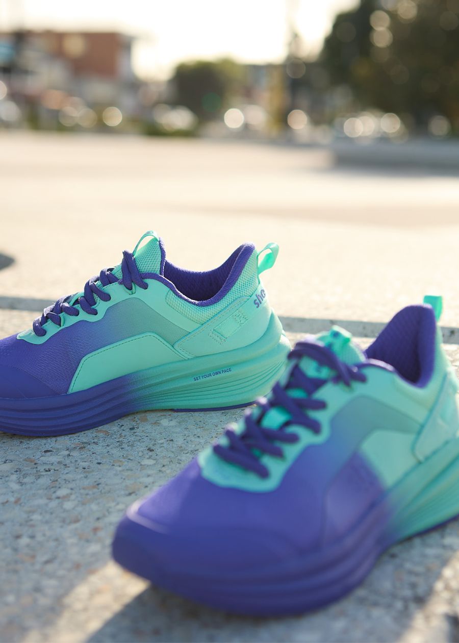Purple and aqua walking shoe on concrete with street in background