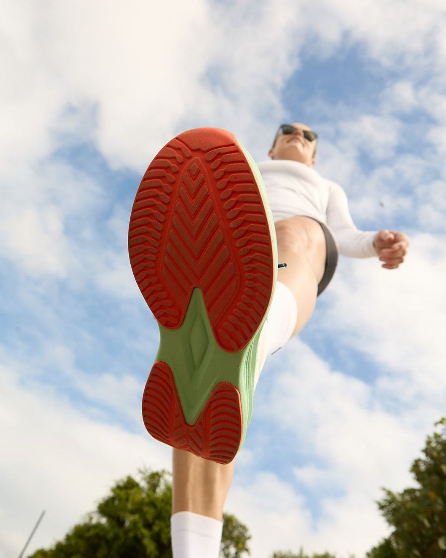 View of orange and mint green slip resistant sole as model steps into the camera