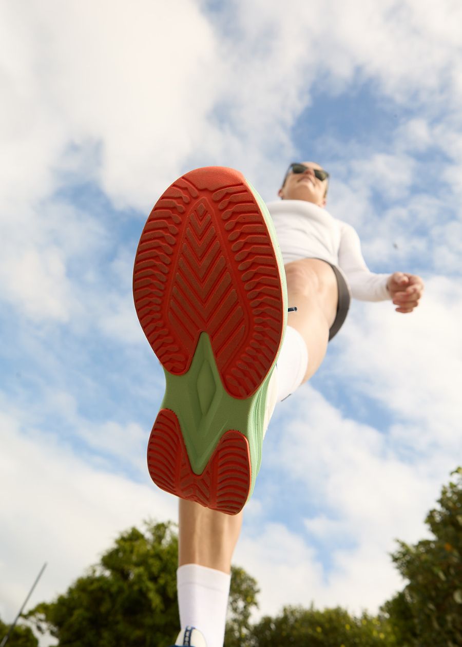 View of orange and mint green slip resistant sole as model steps into the camera