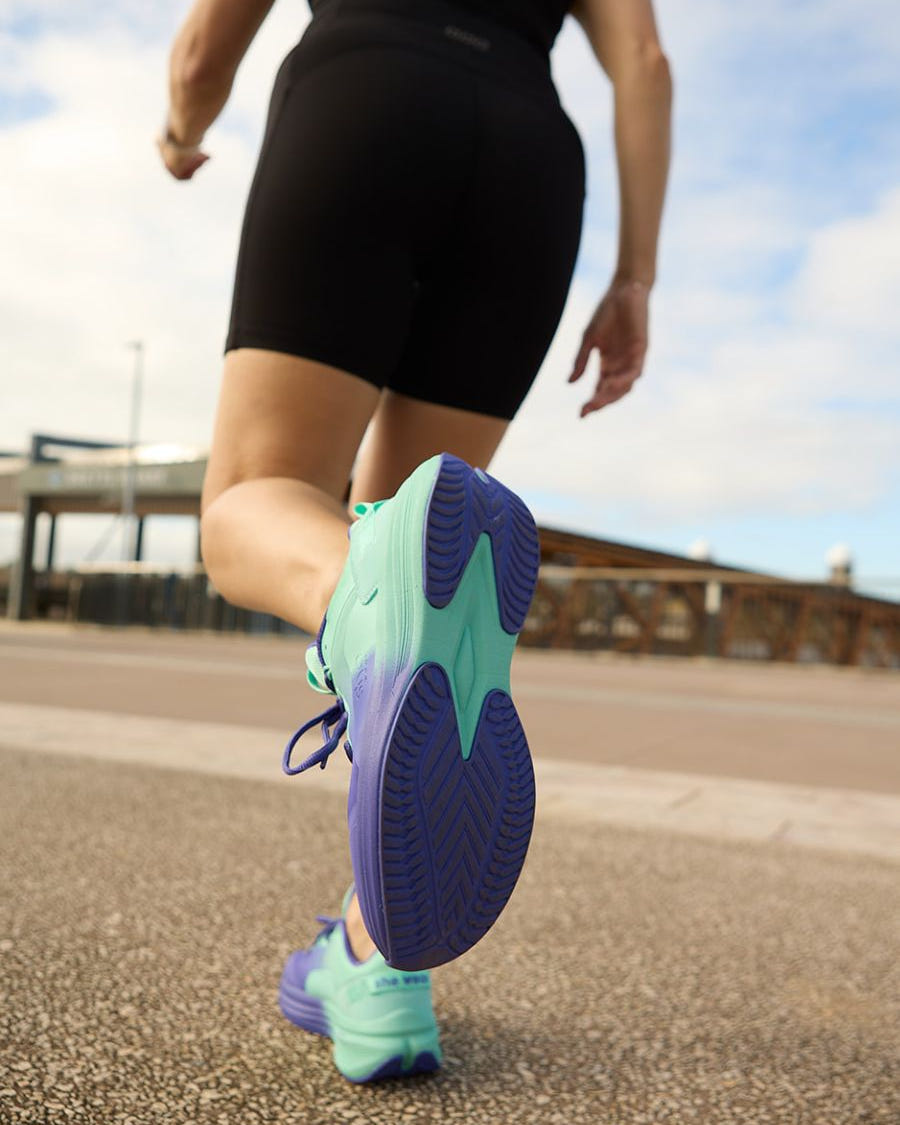 View of purple and aqua slip resistant soles as model is walking on pathway