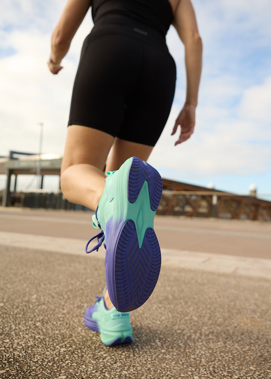 View of purple and aqua slip resistant soles as model is walking on pathway