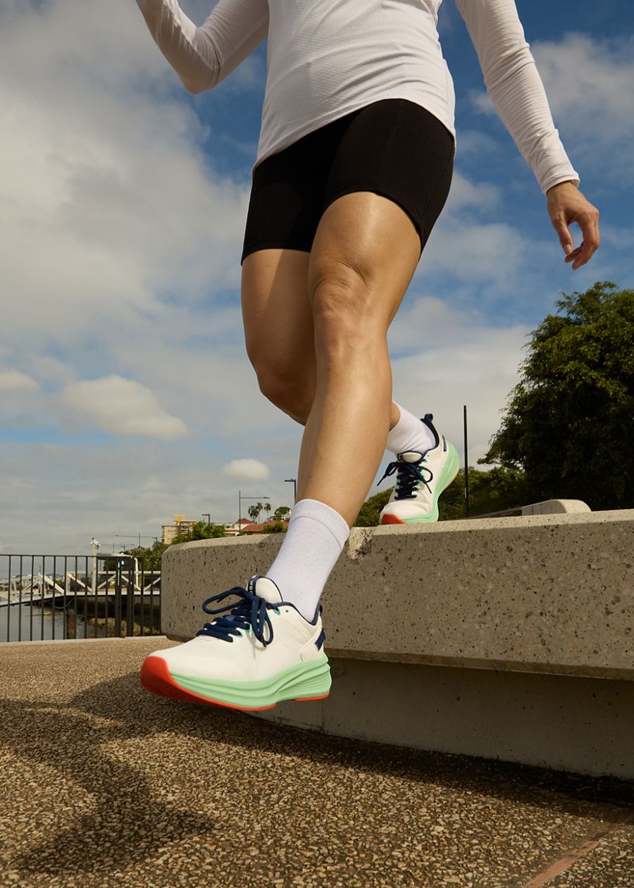 Woman stepping down from stone ledge in black and mint walking shoes.