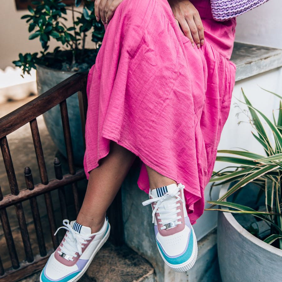 woman sitting in pink dress with she wear pastel coloured rise fashion sneakers