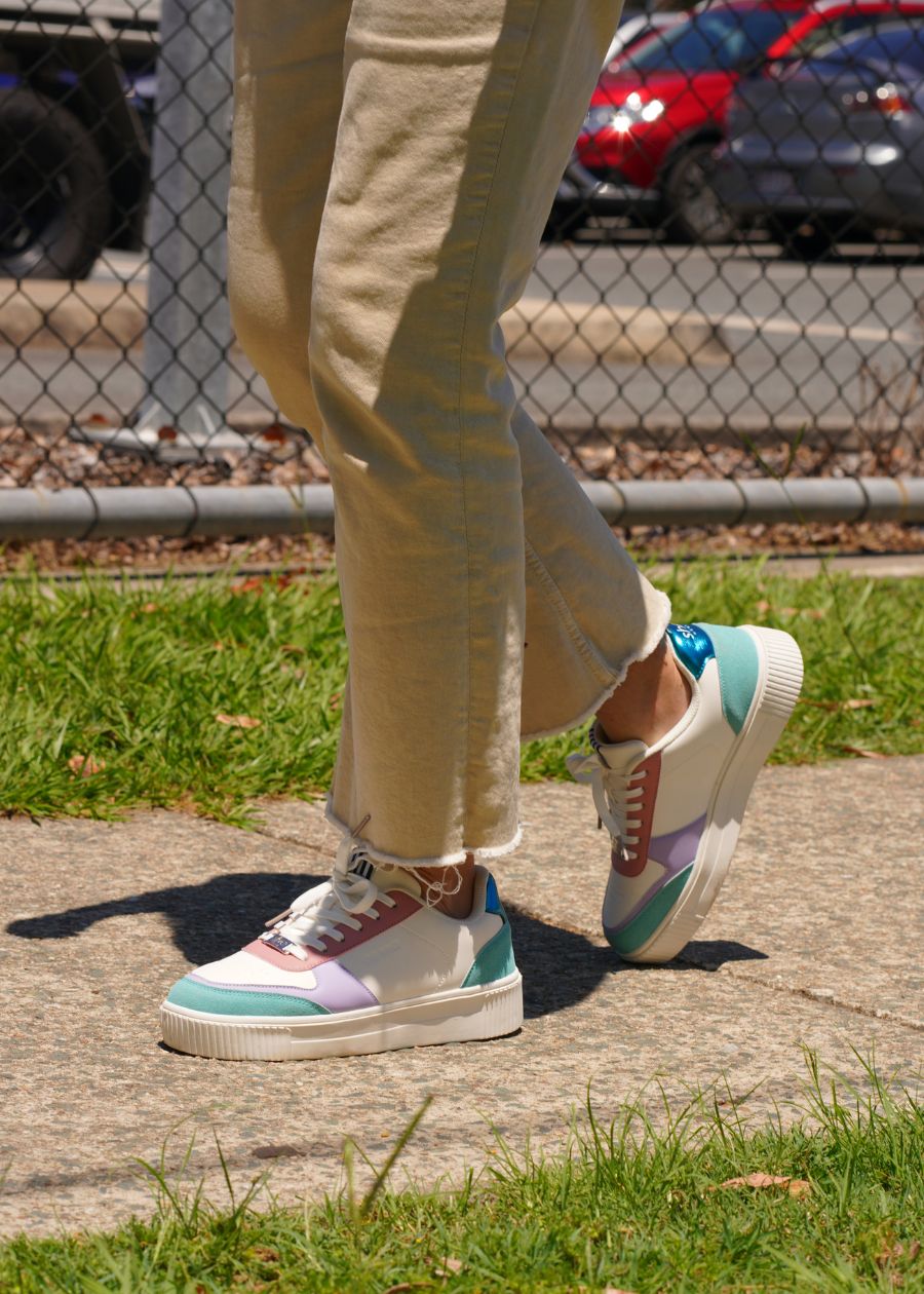 a woman wearing tan jeans and colourful platform sneakers