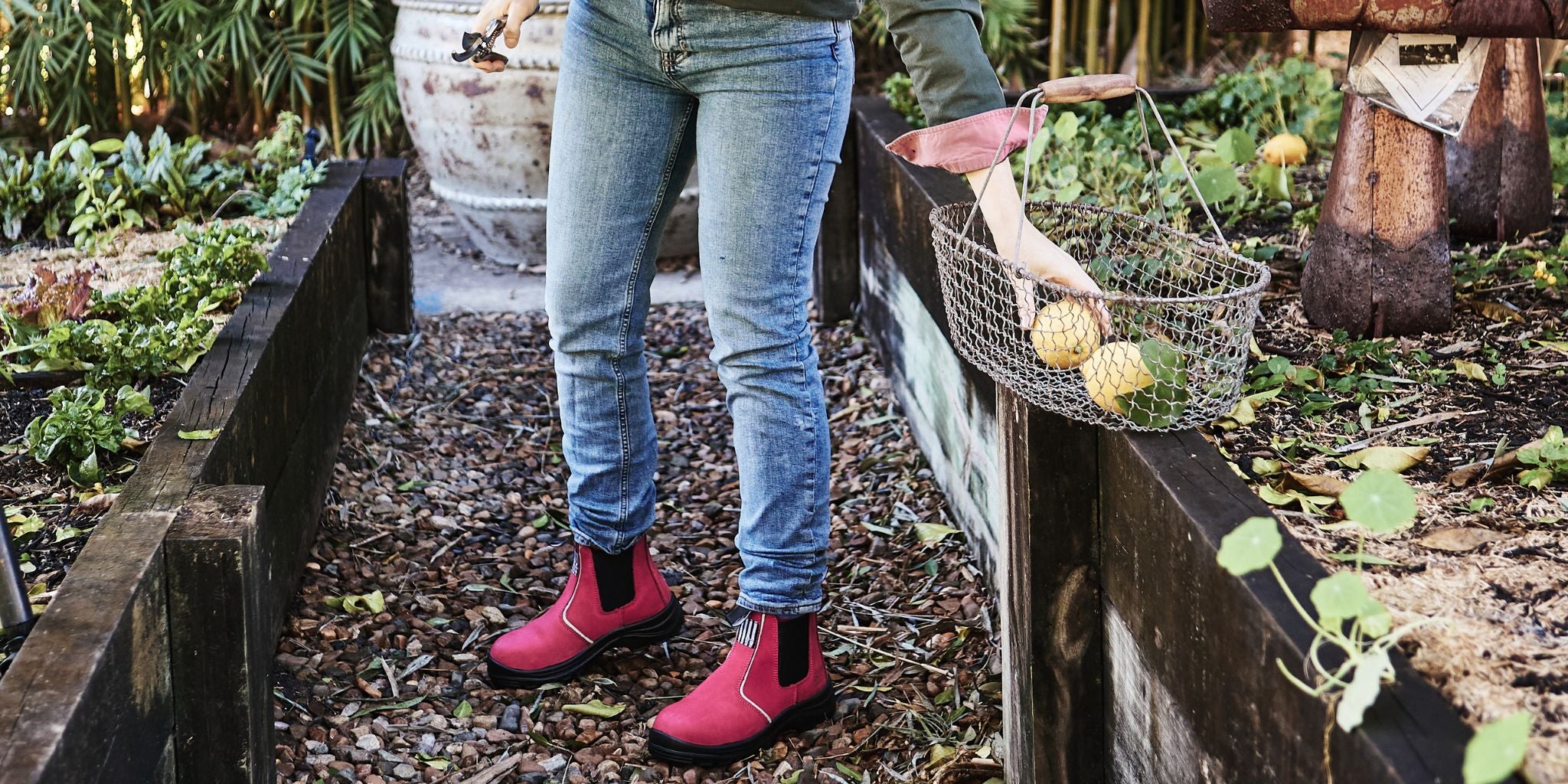 Close up of pink pull-on Inspires work boots on woman who is in garden.