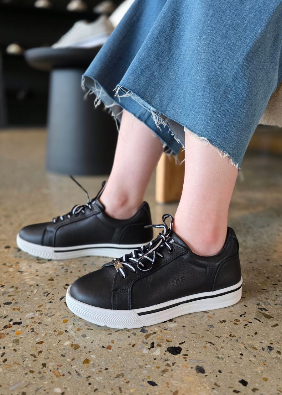 Supports 2 black and white leather occupational sneaker on stone floor