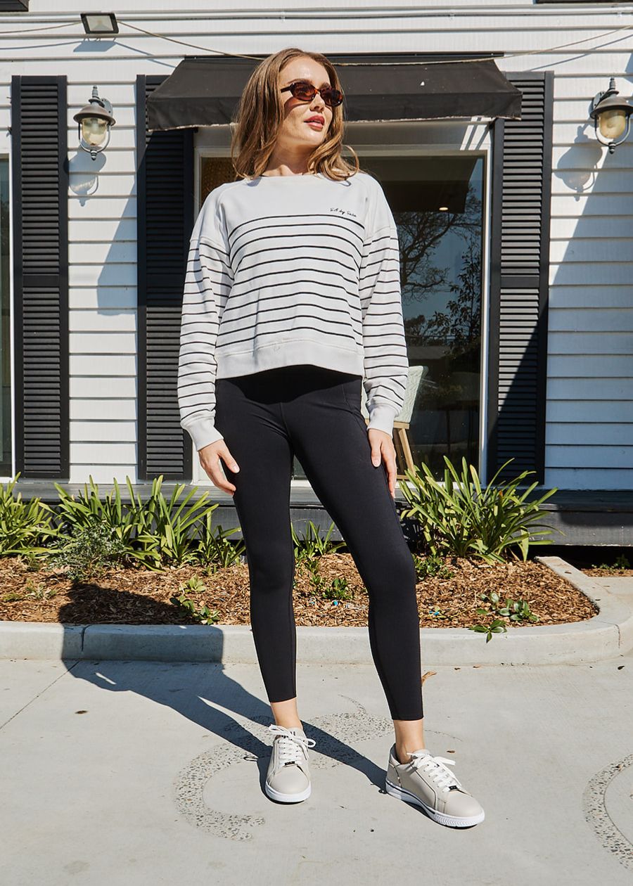 Woman in front of house wearing she wear supportive sneakers in beige.