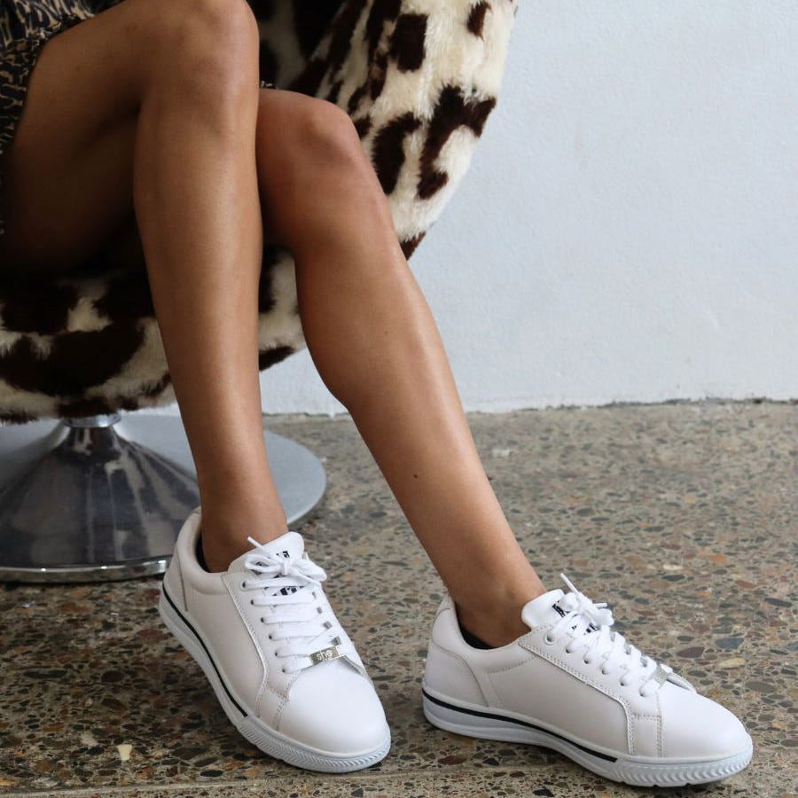 womens supportive white leather sneaker on a woman in a print dress sitting on a chair