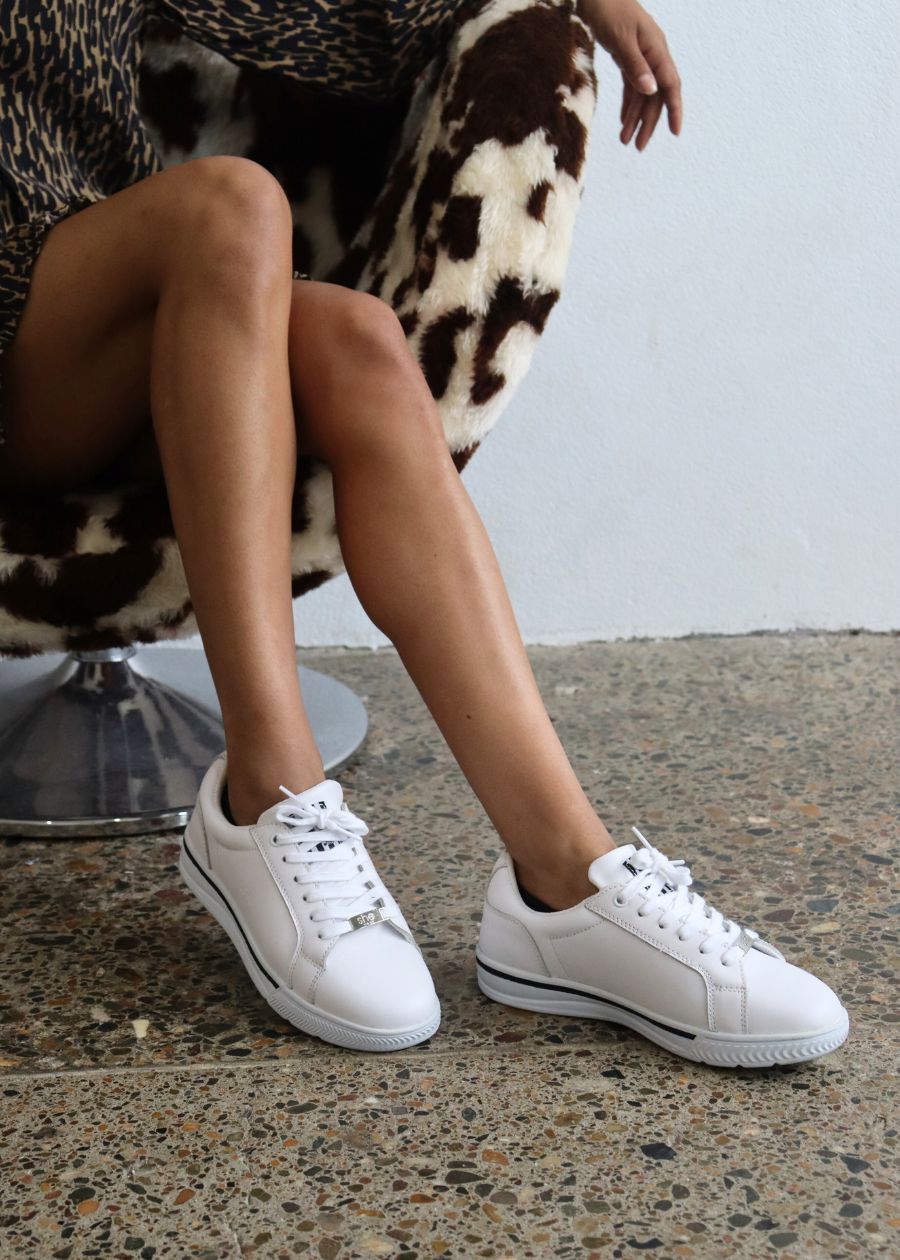 womens supportive white leather sneaker on a woman in a print dress sitting on a chair