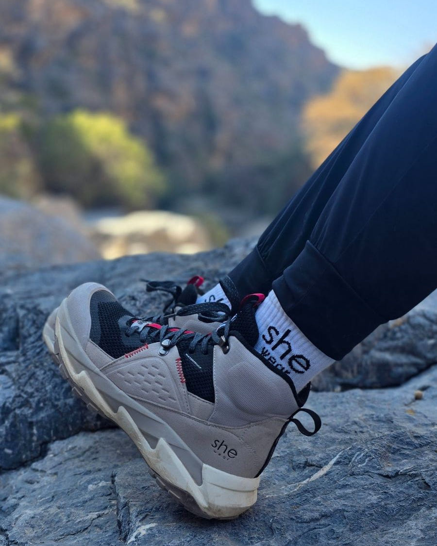 Sitting on top of rocks in grey and black Trek hiking boot.
