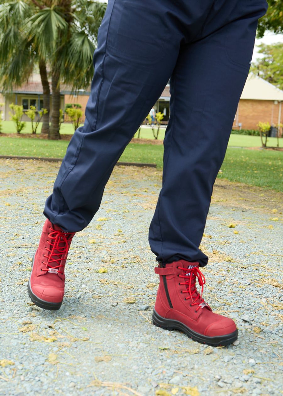 Person walking on gravel in red lace-up safety boots.
