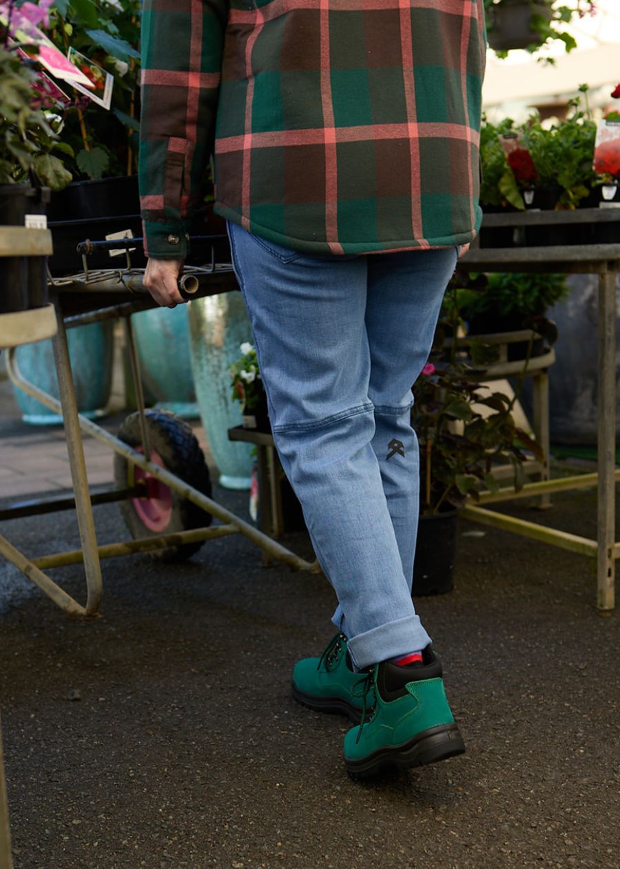 Back view of person gardening in blue denim work jeans.