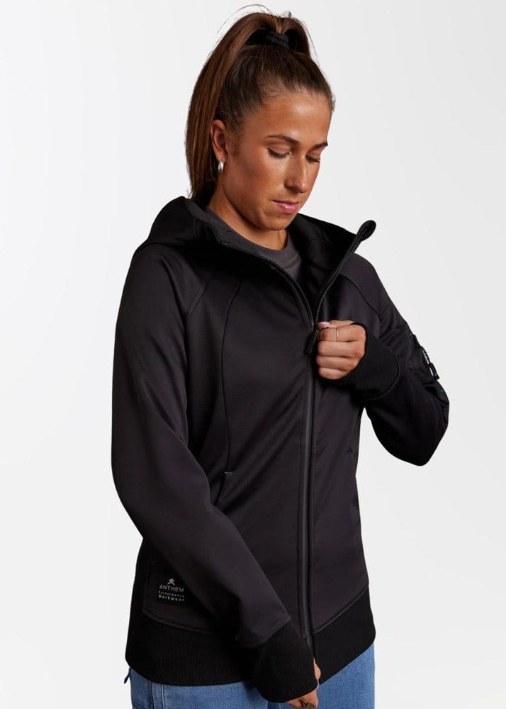 Person wearing a black zip-up hoodie with thumb holes, adjusting the zipper.