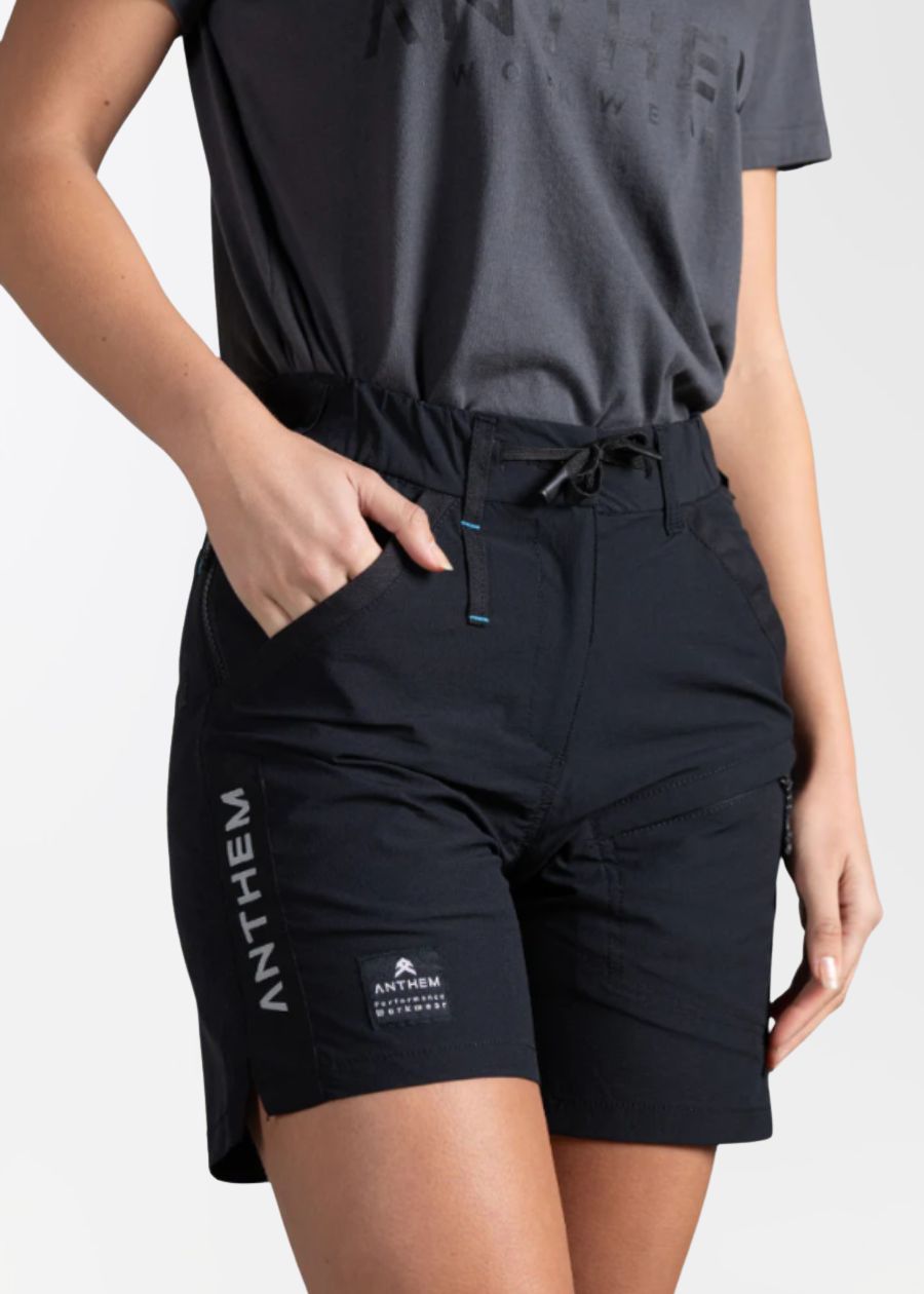 Front view with hand in front pocket of black light weight work shorts by Anthem.