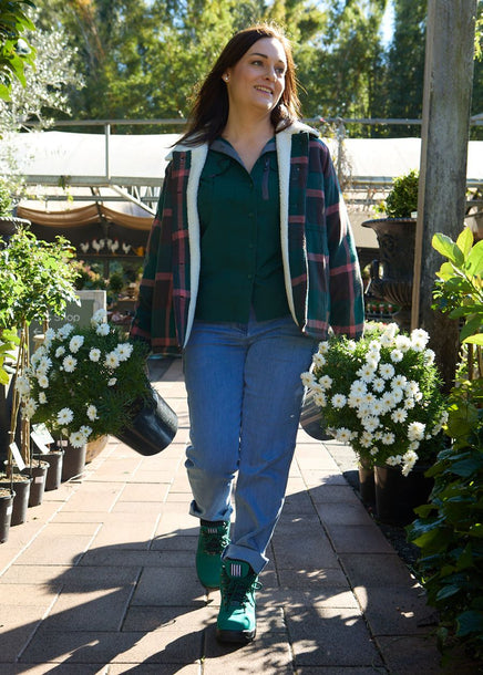 Woman walking through garden in jade green coloured hiker-style, steel cap work boots. 