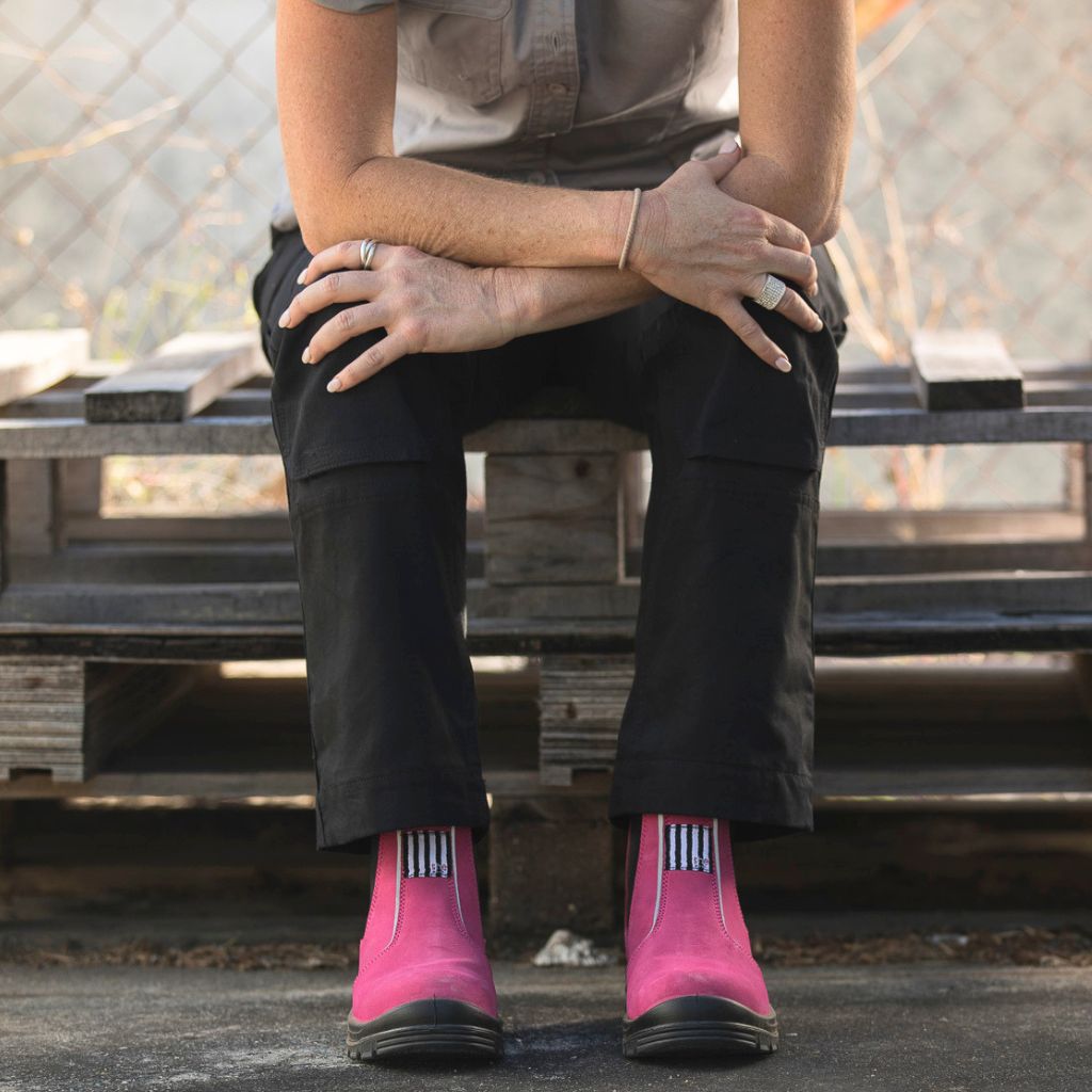 Woman sat down on a wooden pallet wearing pink work boots