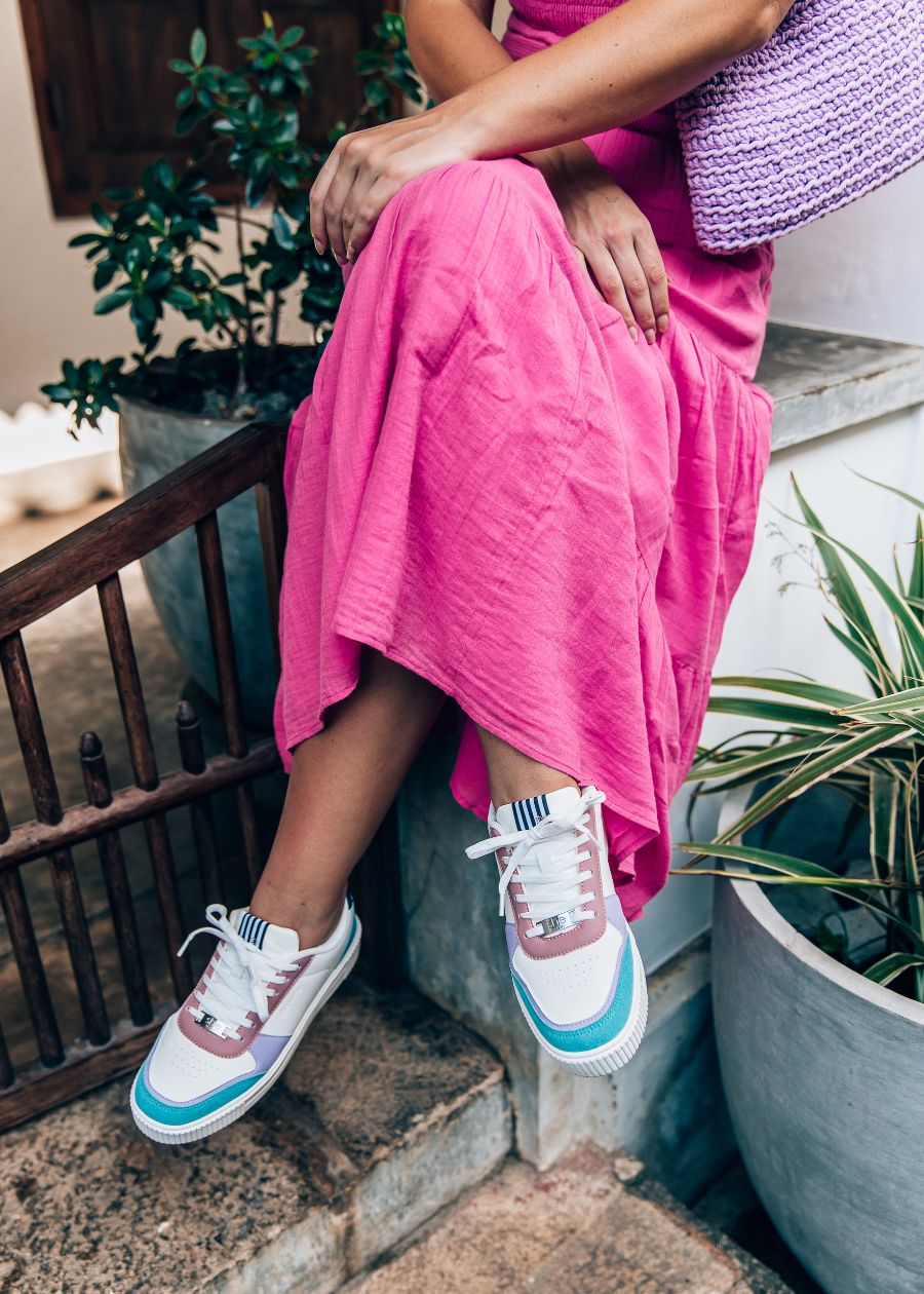 woman sitting in pink dress with she wear pastel coloured rise fashion sneakers