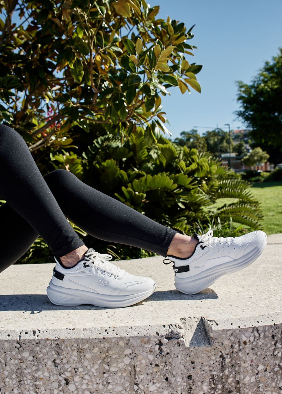 woman sat on concrete bench wearing white walking shoe 