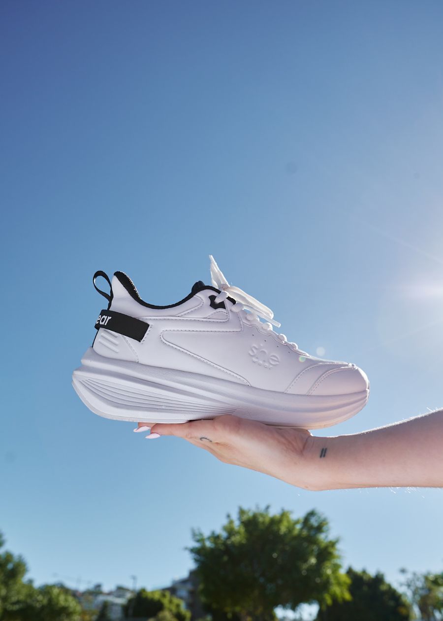 Woman holding white walking sneaker in her hand 