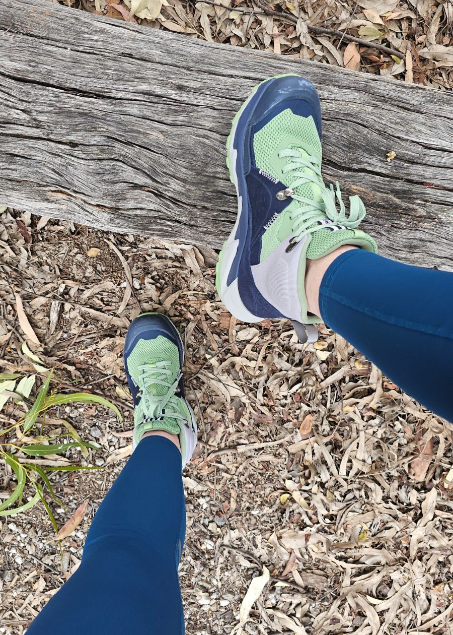 Standing on tree stump in green and navy ankle hiking boots.