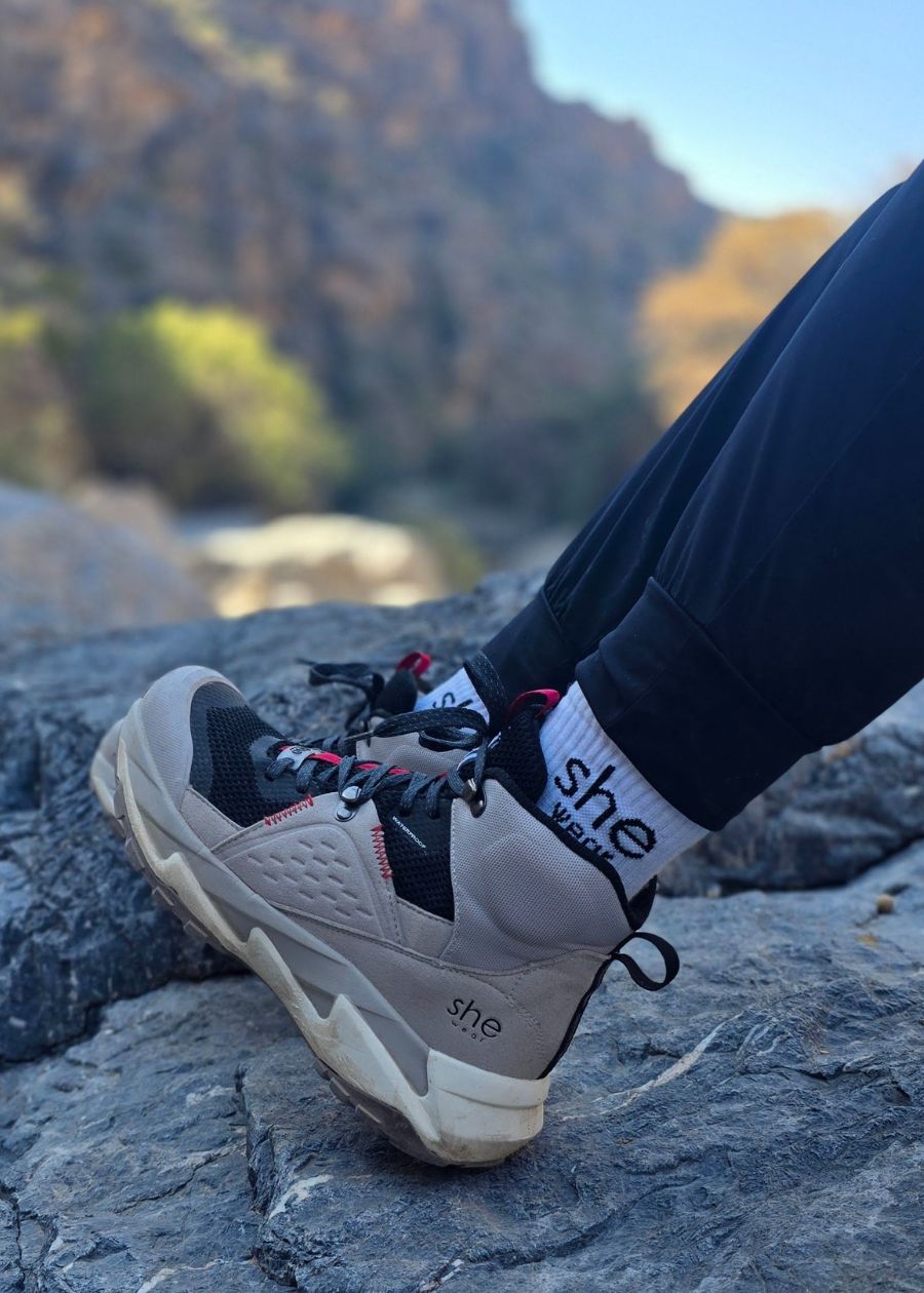 Sitting on top of rocks in grey and black Trek hiking boot. 